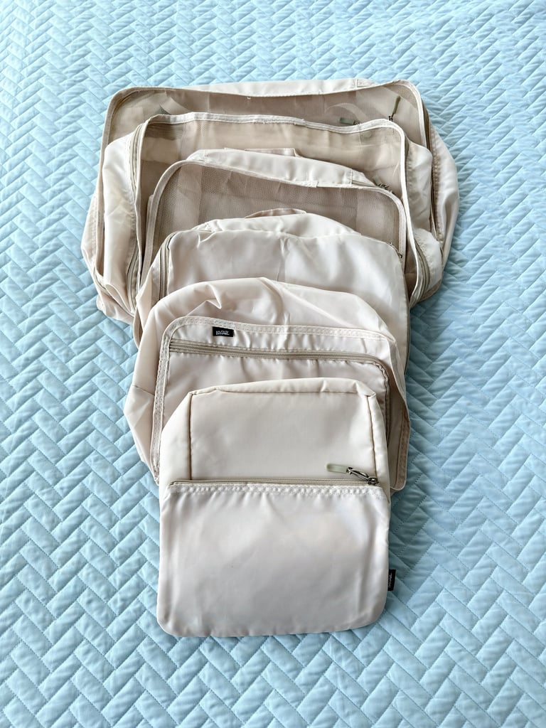 Cream colored packing cubes laid out for organizing clothing during travel