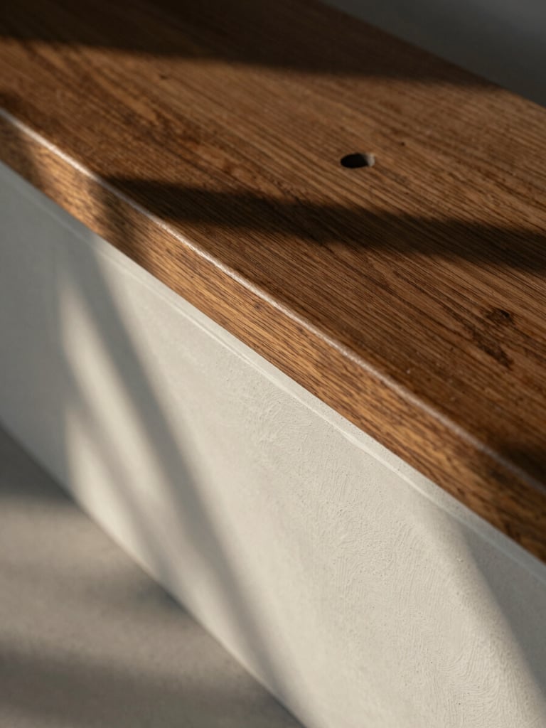 Detail study of hand-applied plaster meeting a dark oak bench, natural late afternoon shadow play, high-angle architectural crop.
