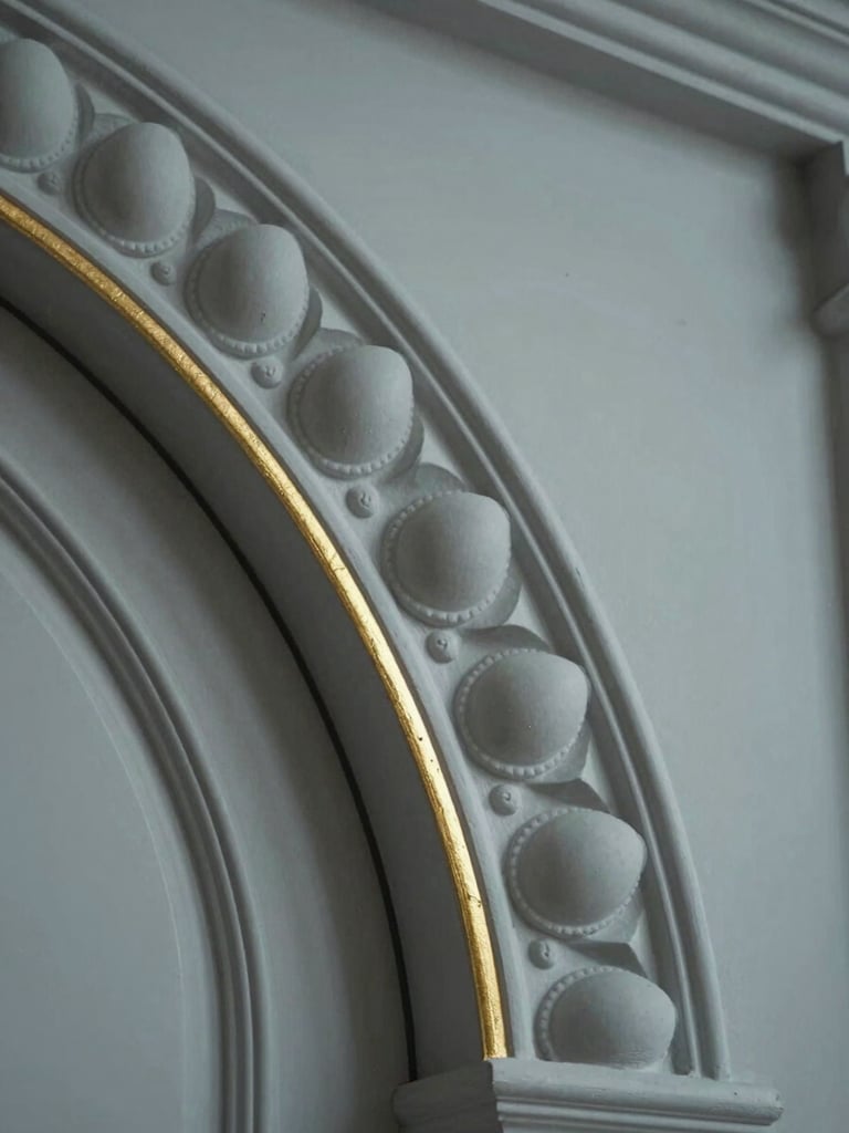 Extreme close-up of a classical door architrave detail — hand-cut plaster egg-and-dart molding, matte finish, a thin gold-leaf line at the reveal edge, cool even studio light, no depth of field blur