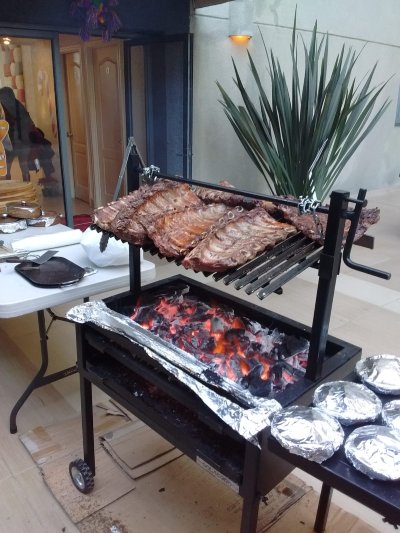 Costillas de cerdo ahumándose sobre brasas calientes en una parrilla de carbón al aire libre.