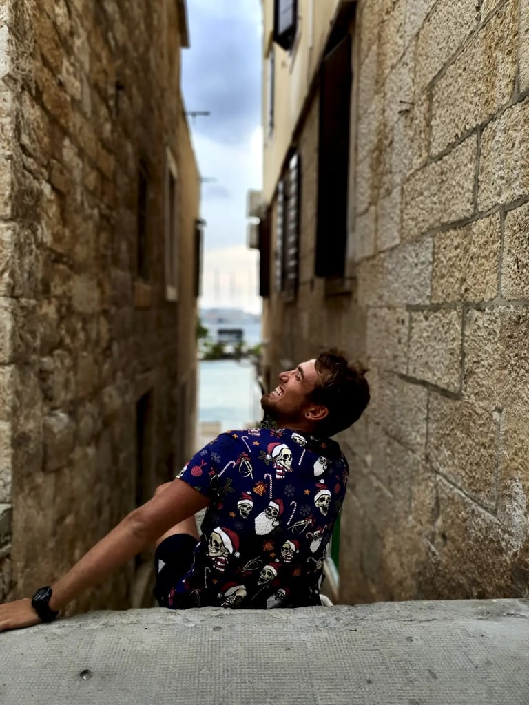 Man smiling while sitting in narrow street of Komiza town on the island of Vis, during a private boat tour from Split Croatia