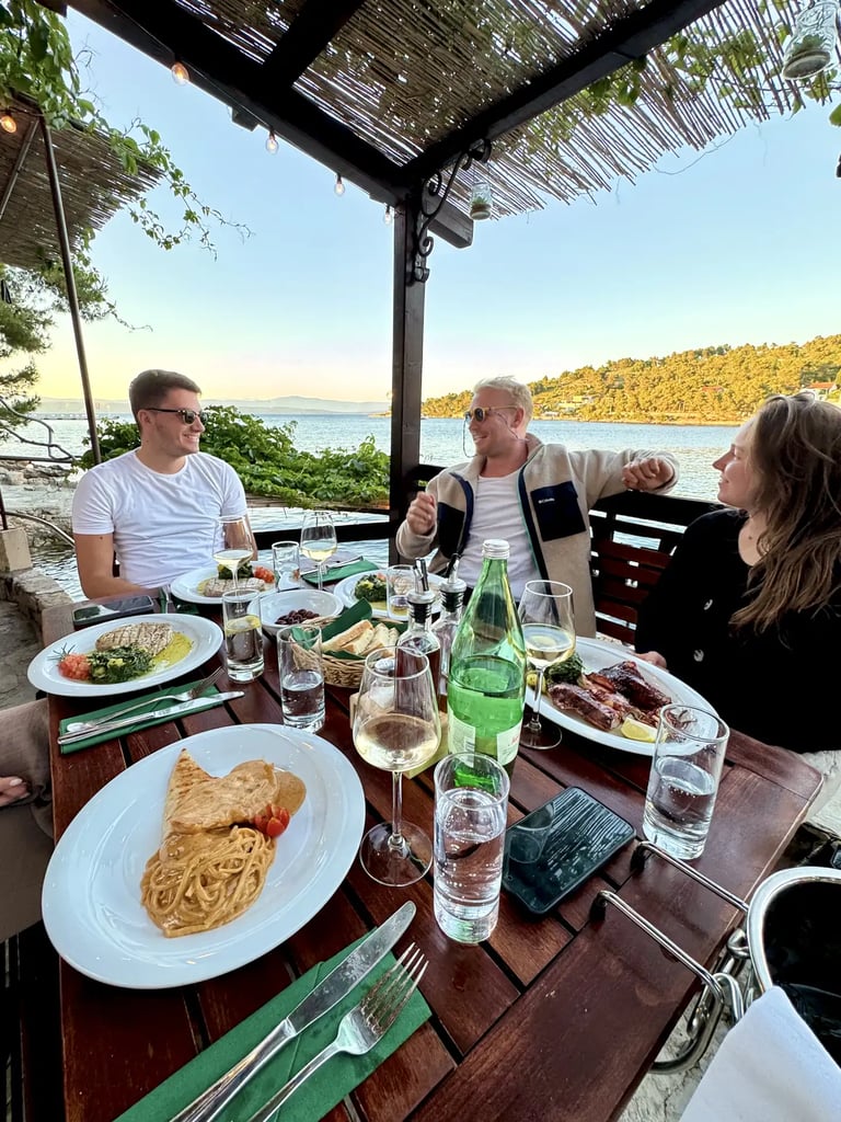 Guests smiling with food on plates at a seaside restaurant on Šolta during a private boat tour from Split