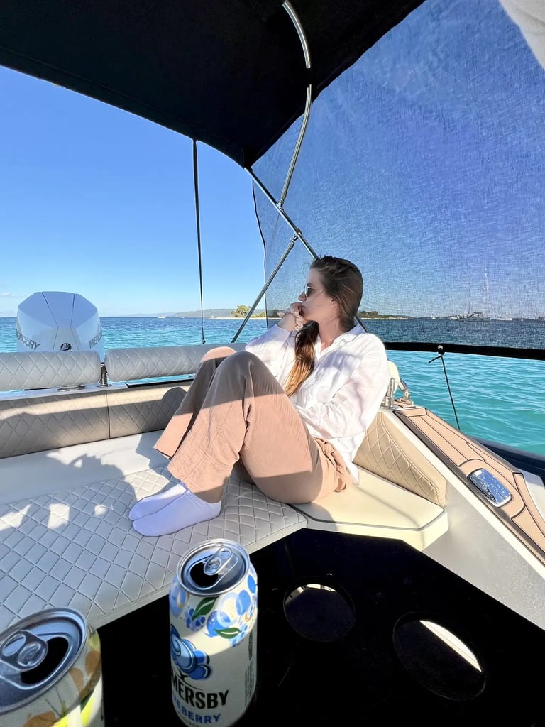Guest relaxing on the stern sundeck of Hunter Pro 800 RIB with sunshade and drinks during a private boat tour from Split.