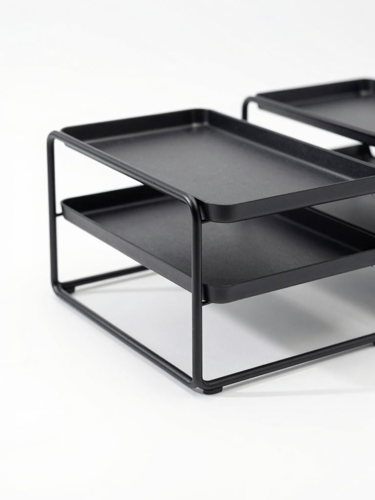 Crisp studio photography of a single matte-black steel desk organizer shot in isolation on a clean white background, bright high-key lighting, soft natural shadows, sharp focus, 50mm lens.
