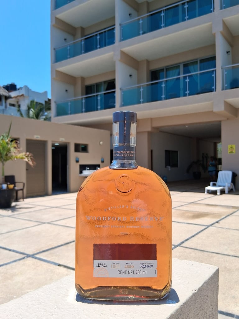 Botella de Whisky con instalaciones de Bungalows Aleday de fondo.