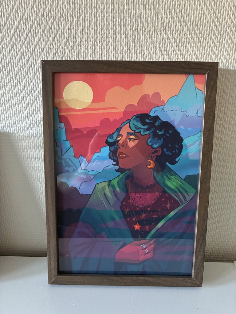Framed fantasy illustration of a woman with blue hair against a sunset mountain landscape.
