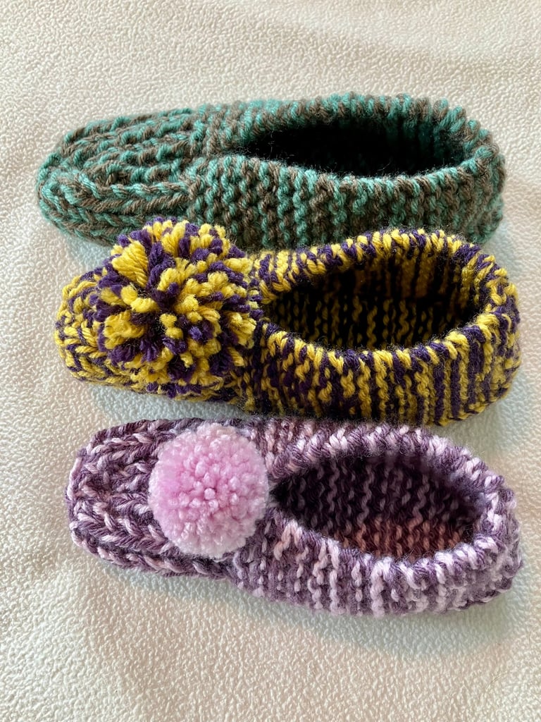 3 single hand knit slippers. Top is green and brown, middle is purple and yellow, and last purple