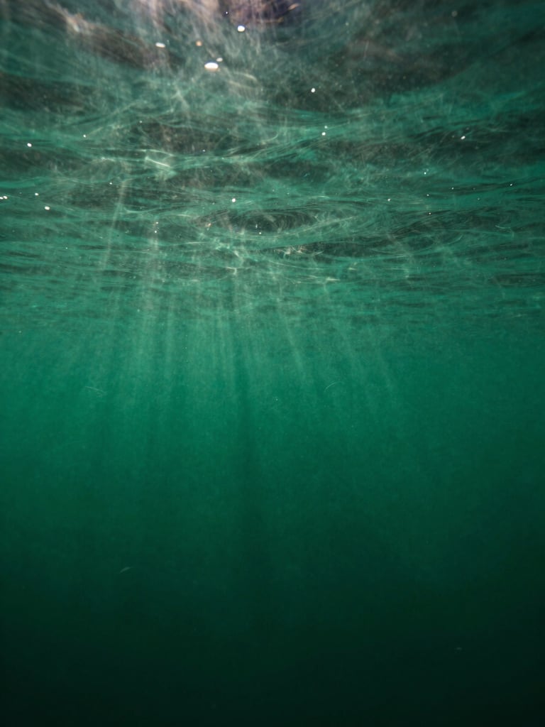 Underwater shot of sunlight rays refracting through deep green lake water, creating ethereal patterns of light, abstract and peaceful