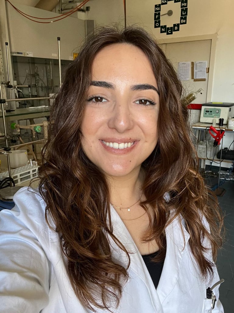 a woman in a lab coat smiling and holding a camera