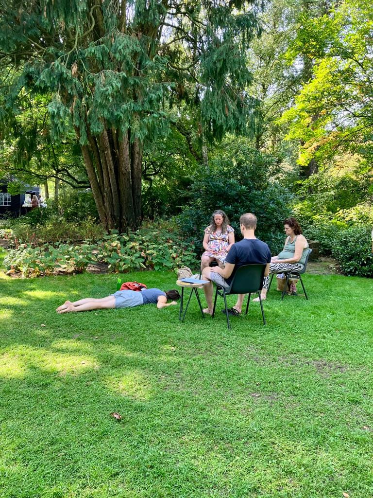 a group of people sitting in chairs in a grassy area