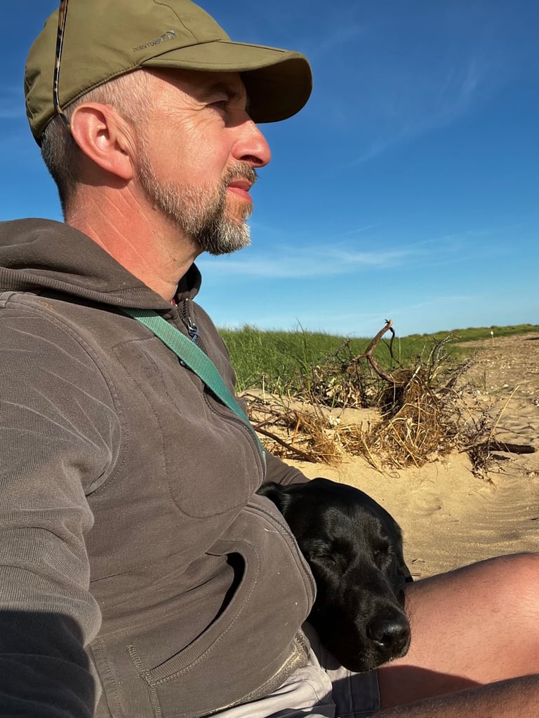a man sitting on a beach with a dog