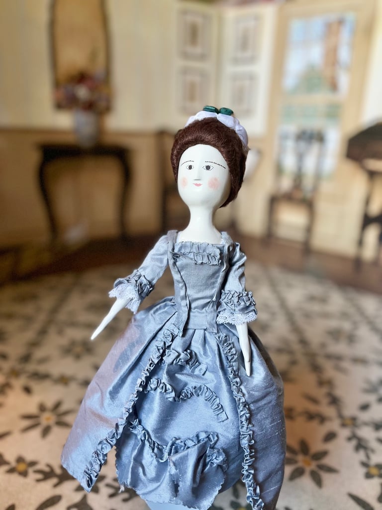 a wooden doll in a blue dress