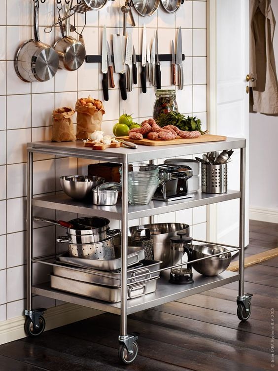 Mobile kitchen island with Stainless Steel Benchtops and two shelves, holding various cooking items.