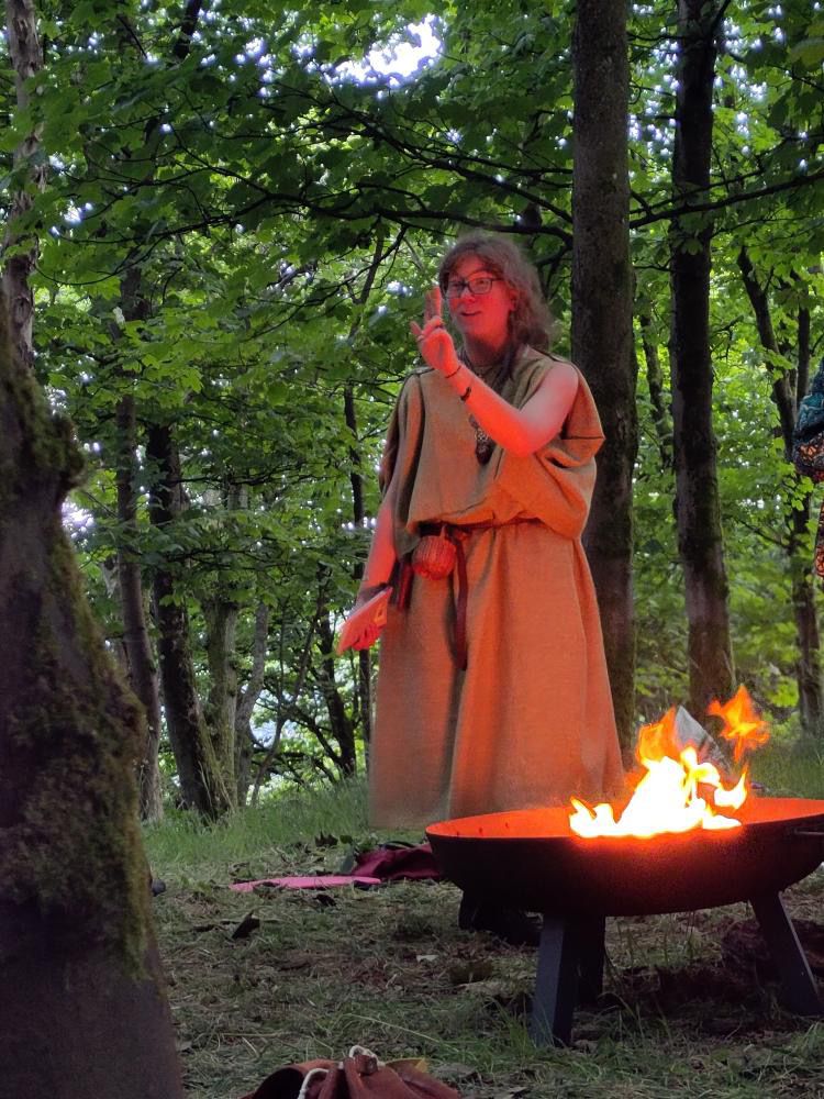 a woman in a robe is standing in front of a fire pit