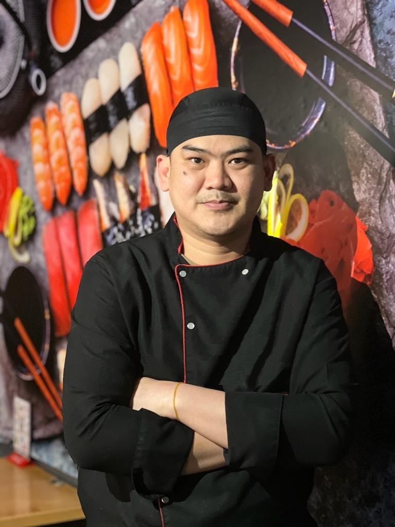 a chef in a black uniform and a black hat