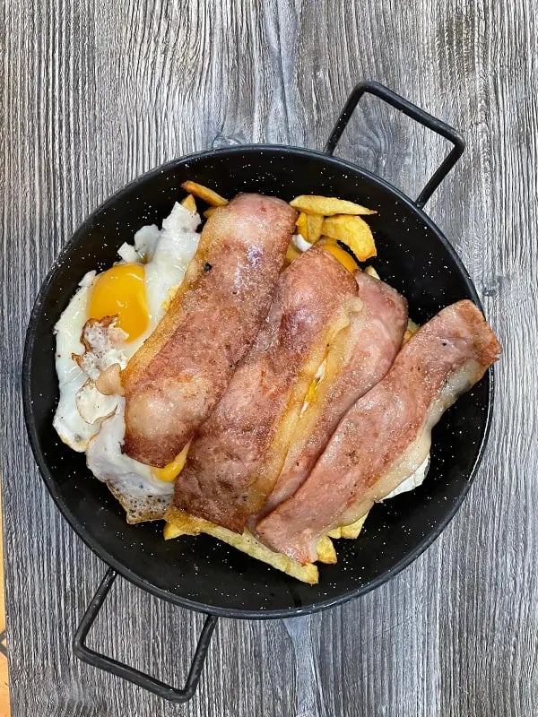 huevos rotos con patatas caseras y beicon frito