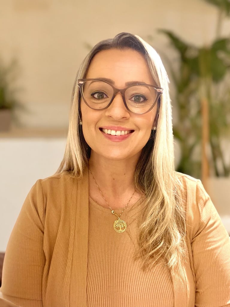 mulher loira de óculos e com um colar dourado sorrindo