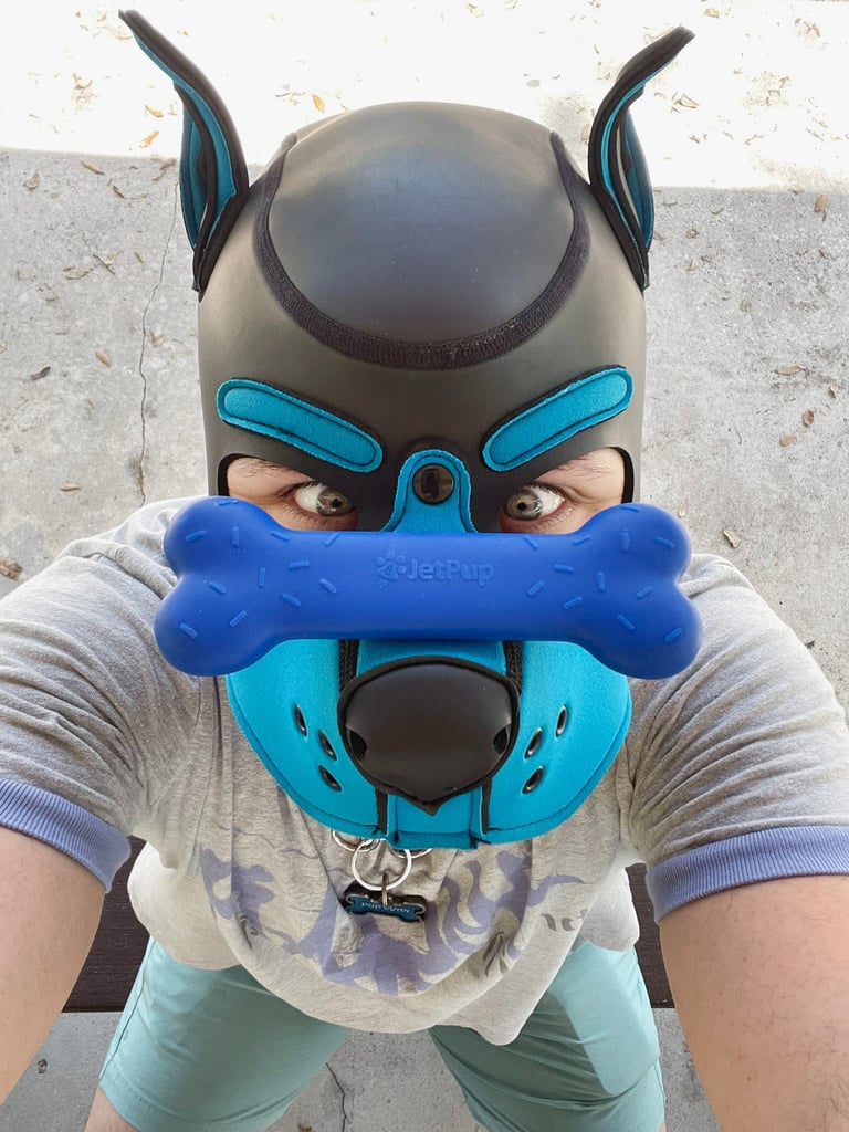 Man in mpup mask with a chew toy balanced on his snout.