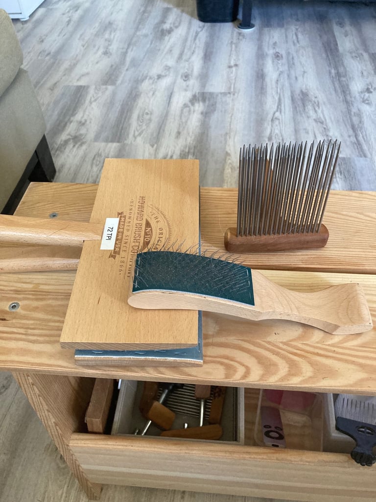 Wool carders and a comb on a wooden bench