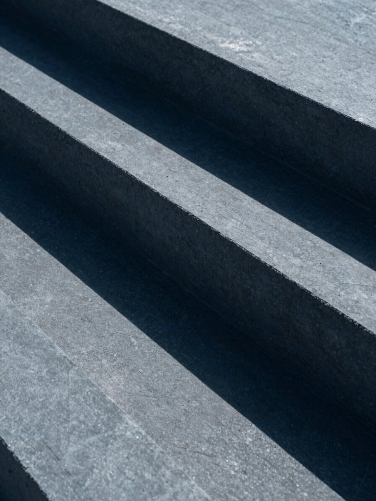 Macro detail of concrete architectural geometric blocks casting sharp diagonal shadows, minimalist composition, slate tones, 35mm