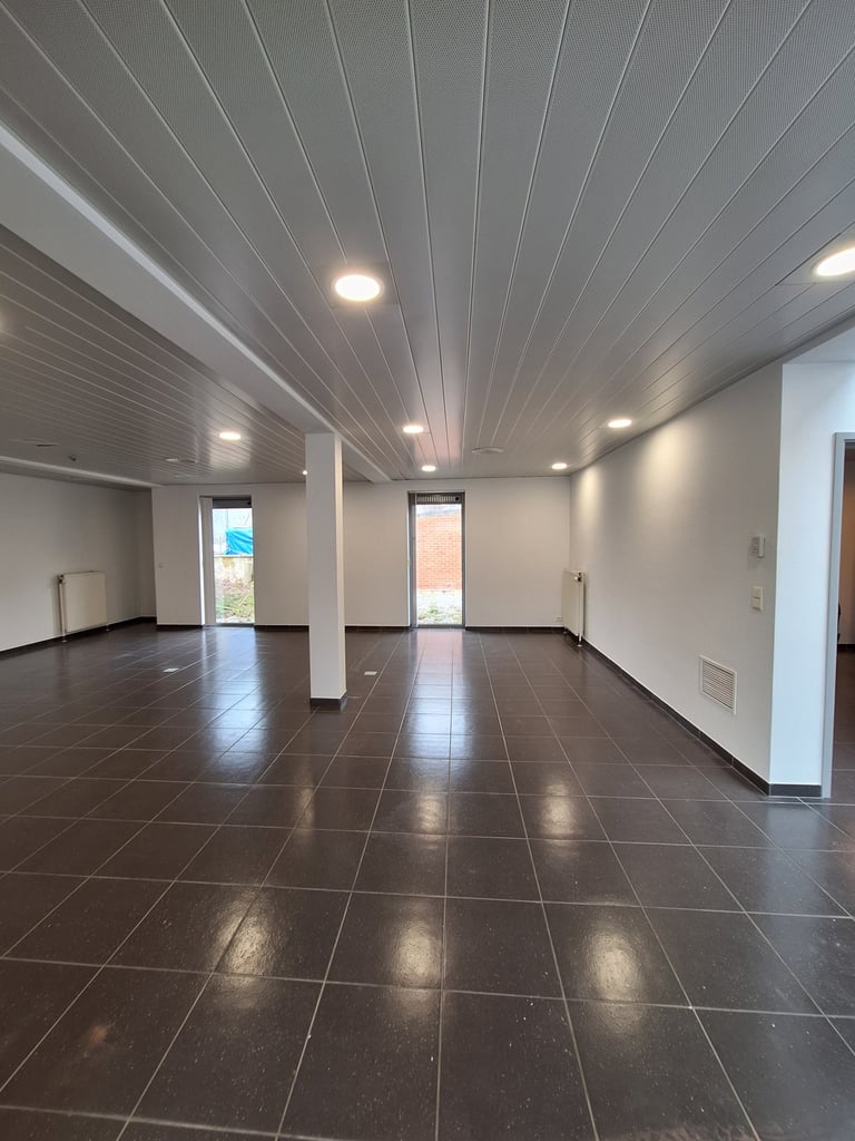 Photo avant transformation de l'espace central avec des murs blancs et des baies vitrées