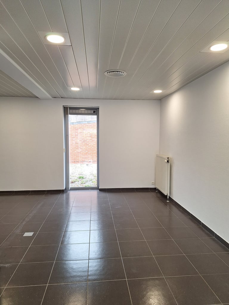 Photo avant transformation de l'espace central avec des murs blanc et du carrelage gris 