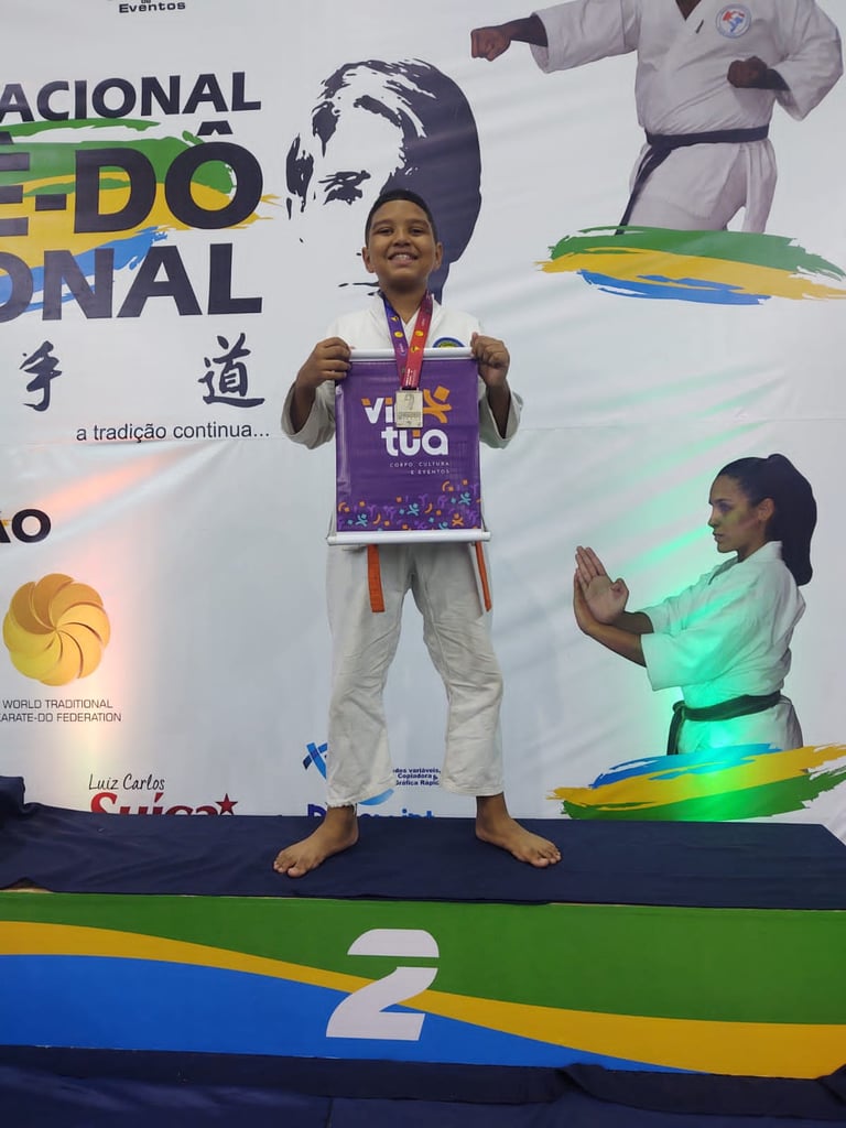 Young karate athlete with a medal standing on a podium at a martial arts championship event.