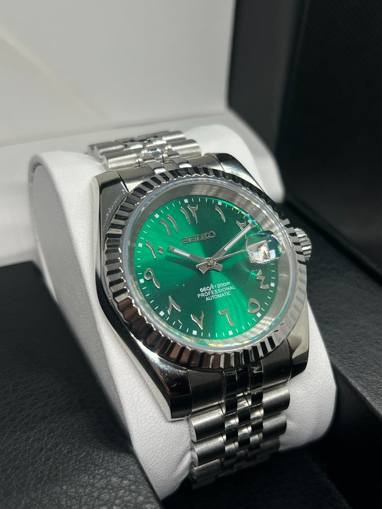 Seiko automatic watch with green Arabic dial and stainless steel jubilee bracelet in a display box.