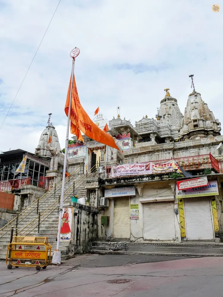 Street view of Jagdish Temple in Udaipur, showing bustling old-city lanes leading to the tall, carved shikhara.