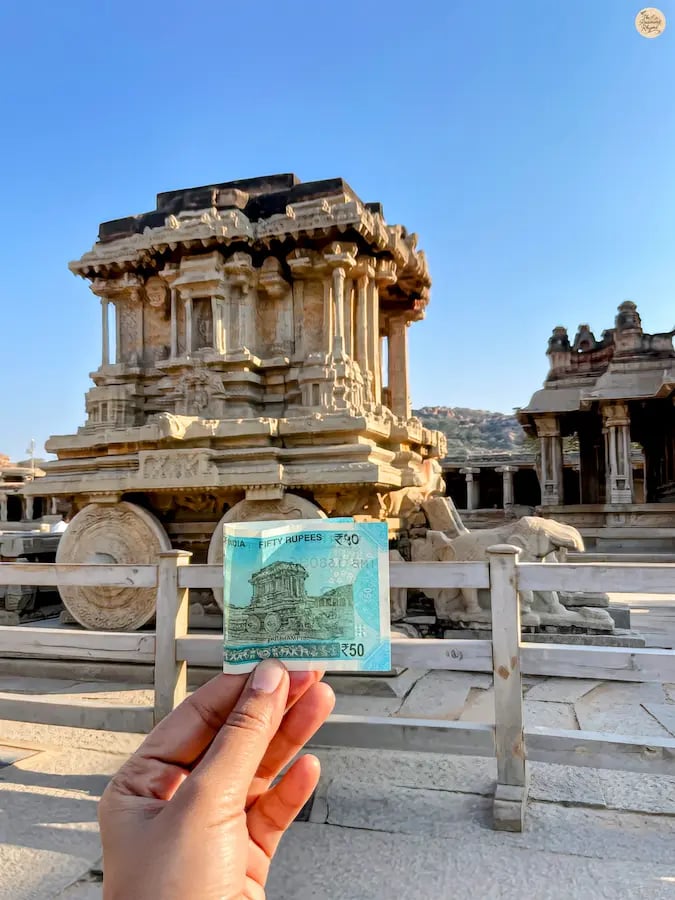 Person holding ₹50 note in front of Hampi’s Stone Chariot, blending history and modern tribute.
