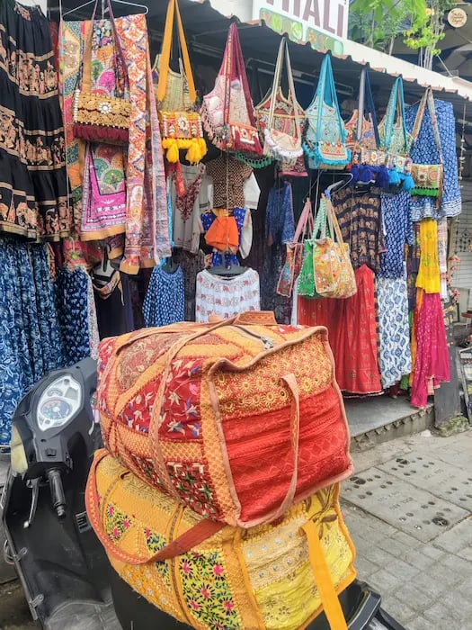 Handcrafted bandhej and leheriya printed cloths and bags displayed in a Udaipur Surajpole bazar.