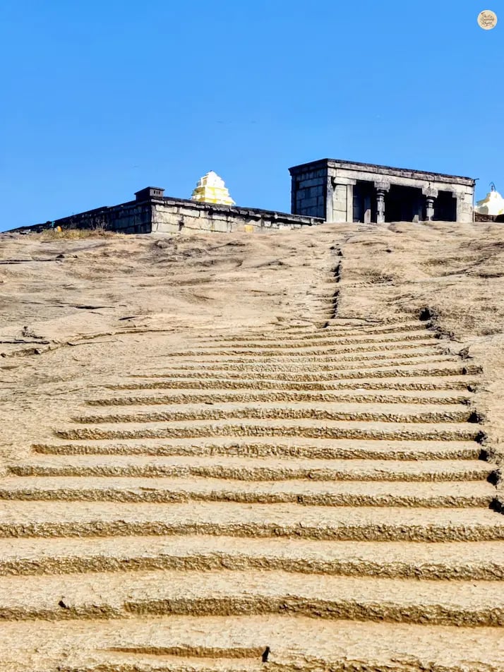 Rock-carved steps leading up to Yoga Nandeeshwara Temple at Nandi Hills, Karnataka, surrounded by greenery and rocky terrain