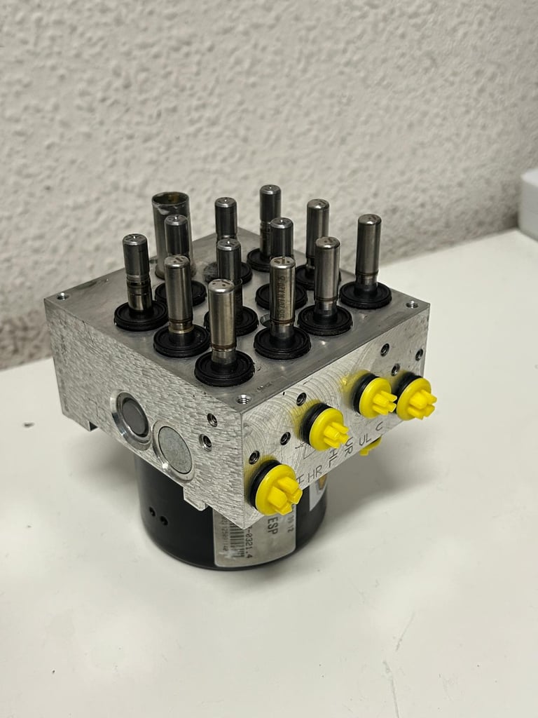 FOTO DESDE ARRIBA DE BOMBA HIDRAULICA DE ABS DESTAPADO Y RECIEN REPARADO CON TAPONES AMARILLOS DE CLAIRICAR EN LOS CANALES