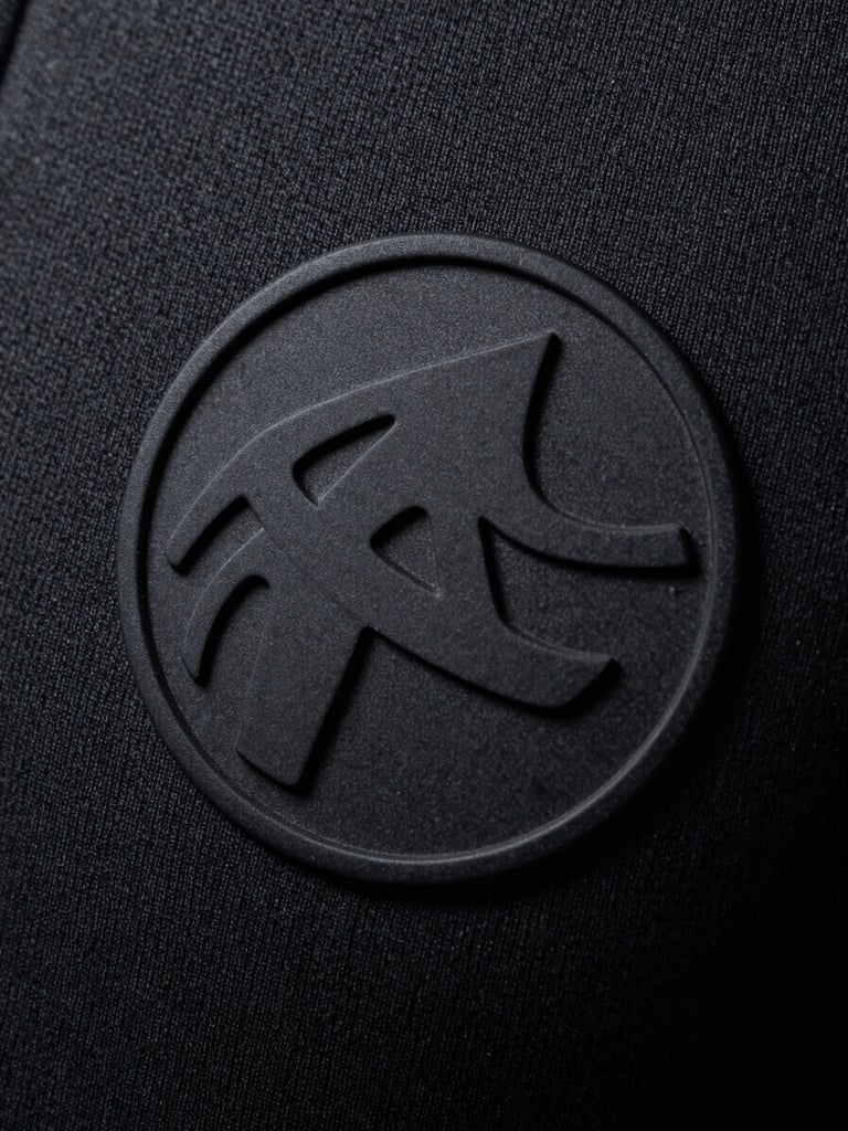 Macro close-up of a high-relief matte black silicone print on heavy charcoal cotton fabric, dramatic side lighting emphasizing texture and depth, 35mm photography
