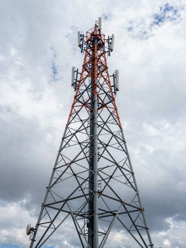 Wide-angle portrait of a massive steel telecommunications tower rising against a dramatic overcast Andean sky, clean industrial composition