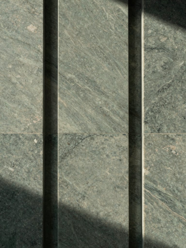 Tactile close-up of a sleek travertine marble entryway with soft diffused morning light, architectural symmetry, 35mm