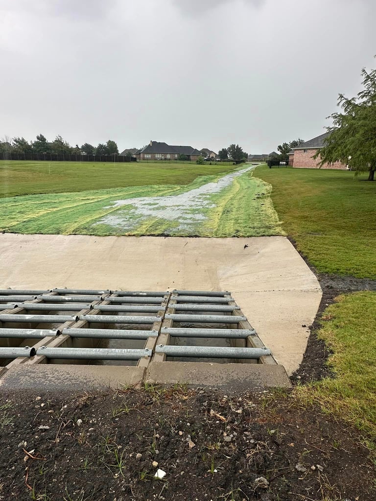 Concrete drainage channel with metal grate.