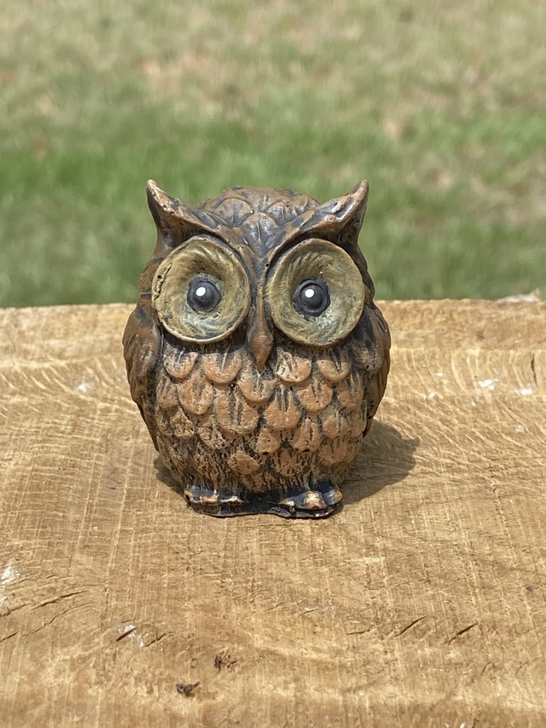 Small brown decorative concrete owl figurine.