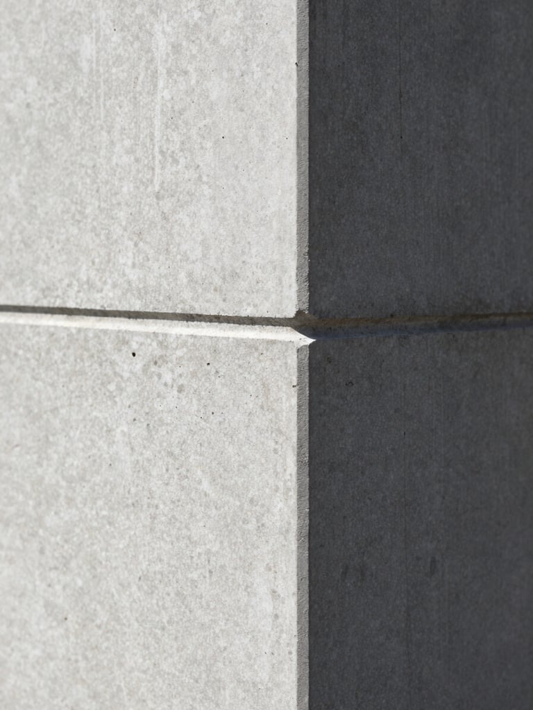 Macro close-up of a structured architectural concrete corner, sharp directional shadows, minimalist and precise, high-contrast.
