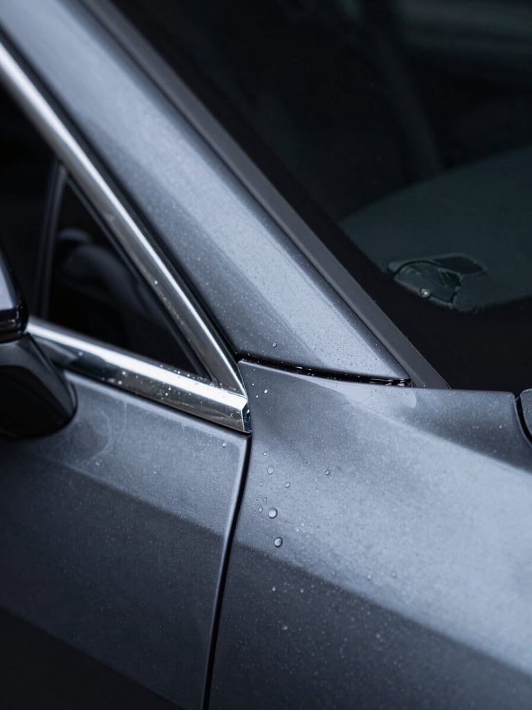 Extreme close-up macro shot of a vehicle paint protection film edge transition on a dark charcoal car panel, cool studio side lighting revealing the film's invisible boundary against the original paint, dark background, 2-3cm framing showing material clarity and zero air bubble installation