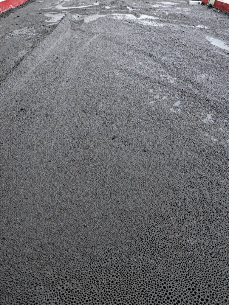 Macro shot of freshly poured cellular foam concrete texture showing uniform micro-bubble structure, clean industrial setting, high-contrast lighting.