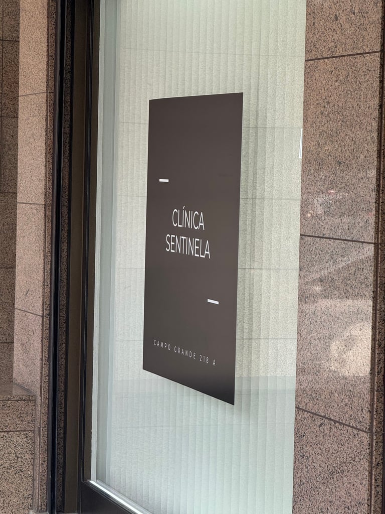 Black signage for Clínica Sentinela medical clinic mounted on a glass storefront in Campo Grande.