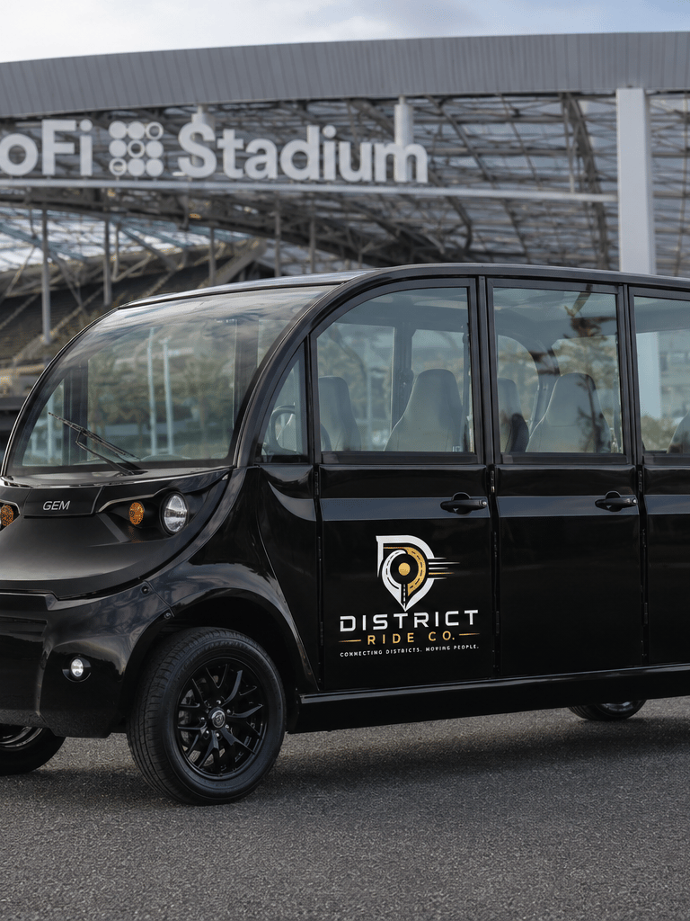 Black GEM electric passenger shuttle parked in front of SoFi Stadium in Los Angeles for event transportation.