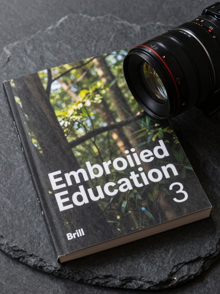 High-resolution cover of the book 'Embodied Education' published by Brill, resting on a dark slate surface, soft natural side lighting.