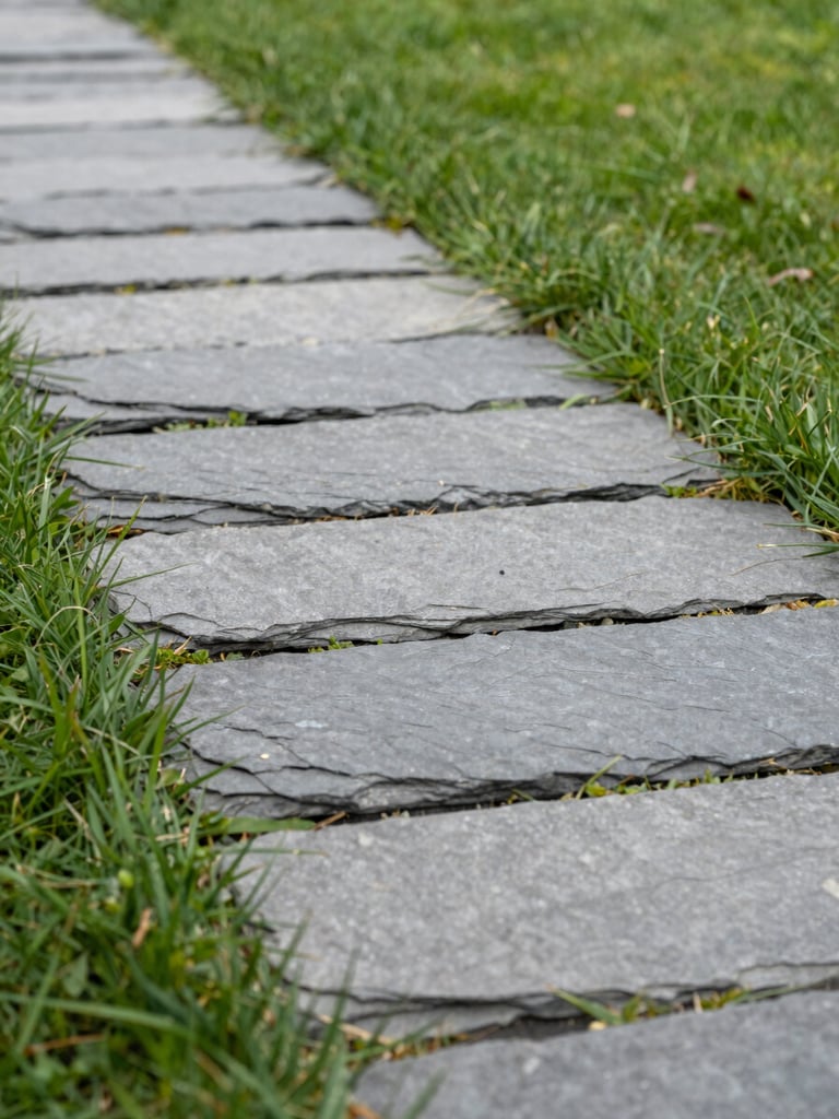 Low-angle architectural shot of perfectly aligned slate grey paving stones meeting lush green grass, overcast daylight, sharp edges, shallow depth of field, 35mm