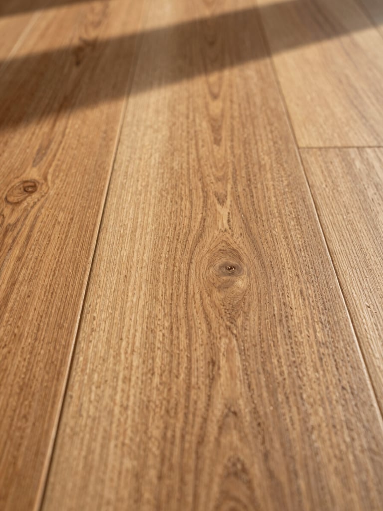 Extreme close-up of oak hardwood flooring, tight framing on the grain and beveled edge detail, warm north-facing daylight raking across the surface to reveal natural wood texture and finish, right side of frame