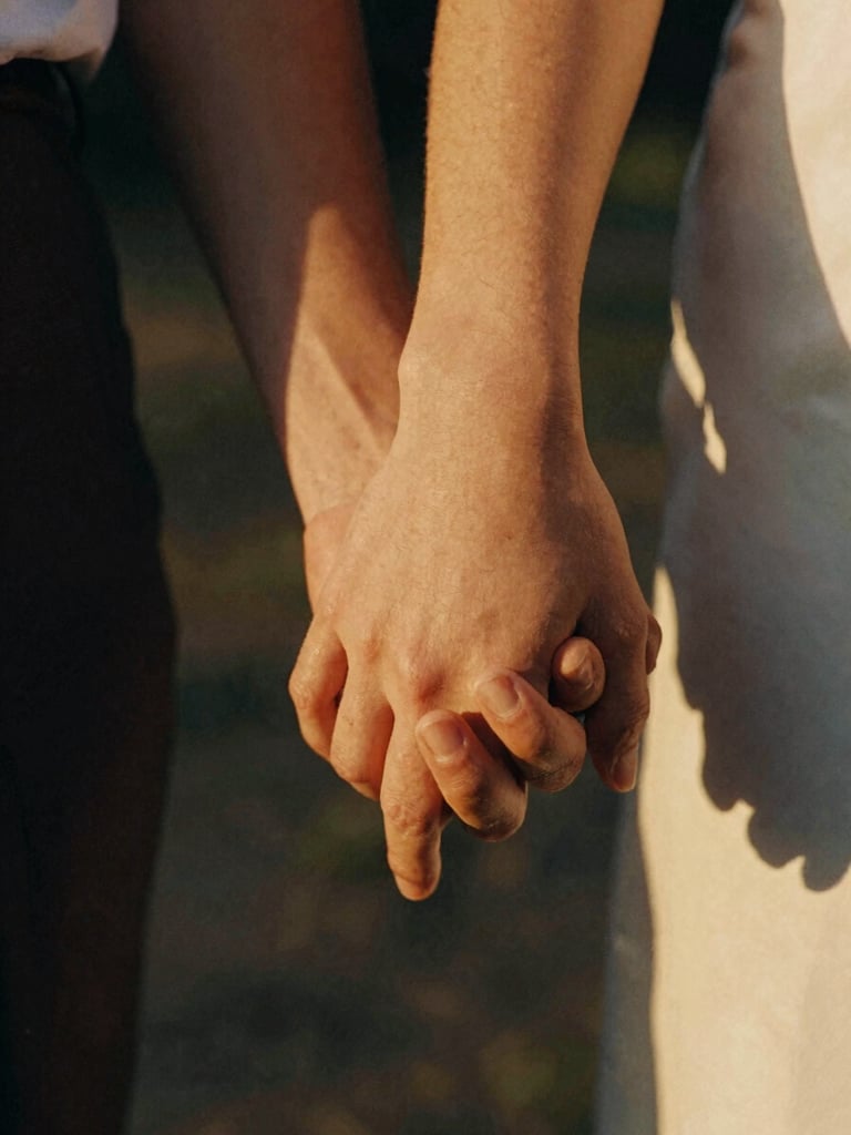 Close-up cinematic 35mm film photograph of a couple's hands gently intertwined, warm golden-hour light, soft grain, shallow depth of field.