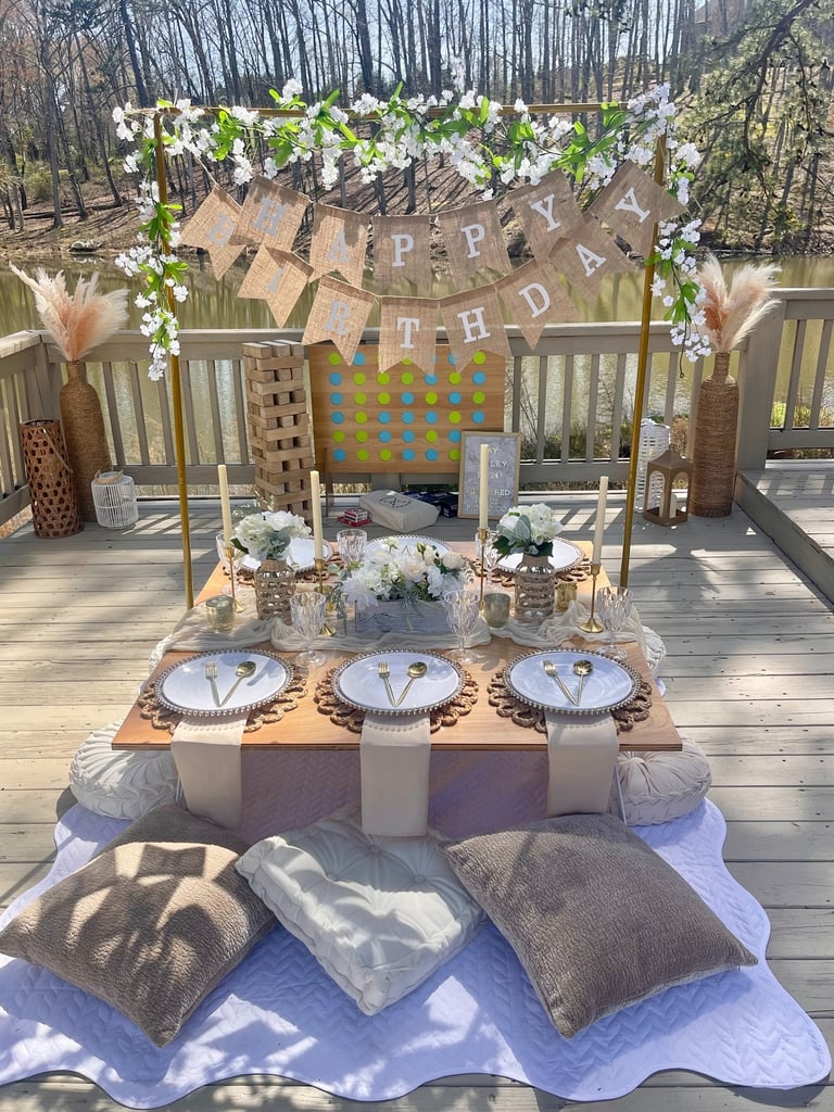 Outdoor neutral birthday party setup elevated picnic rental service with layered place settings