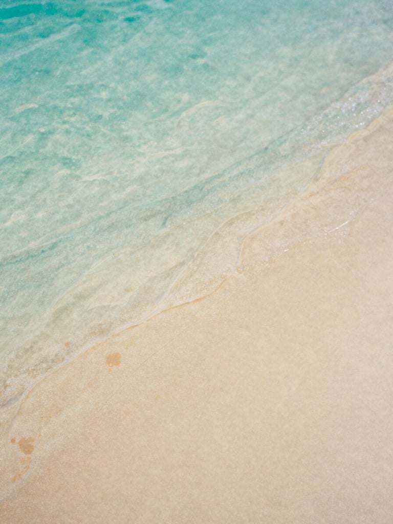 A close-up of soft watercolor textures, flowing turquoise and warm sand pigments blending gently on textured paper, natural daylight, 35mm