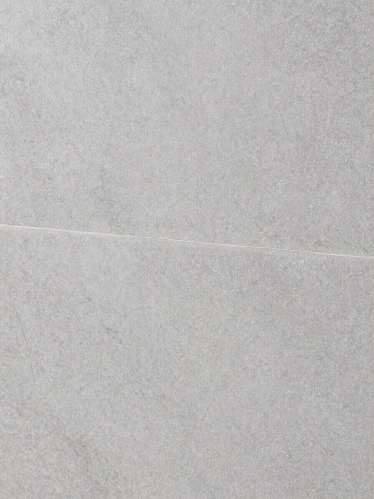 Macro close-up of premium textured grey porcelain tile, sharp focus on glaze detail, neutral studio lighting, architectural minimalist style
